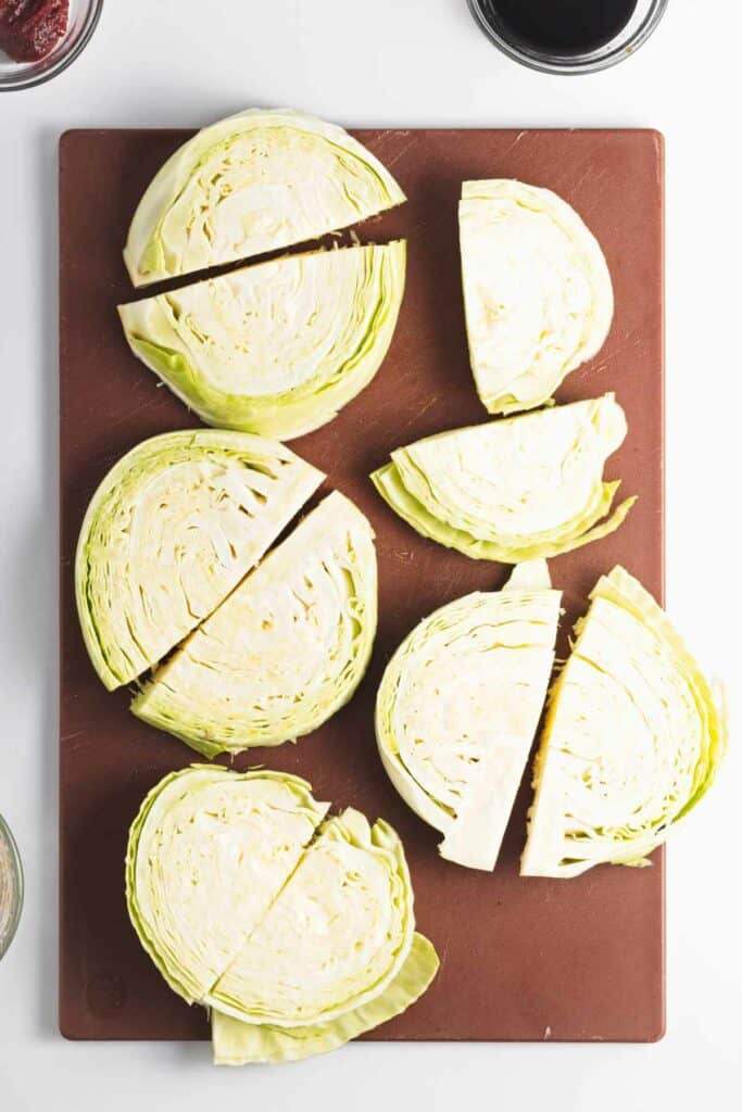 Sliced cabbage on a brown cutting board, ready to be drizzled with gochujang.
