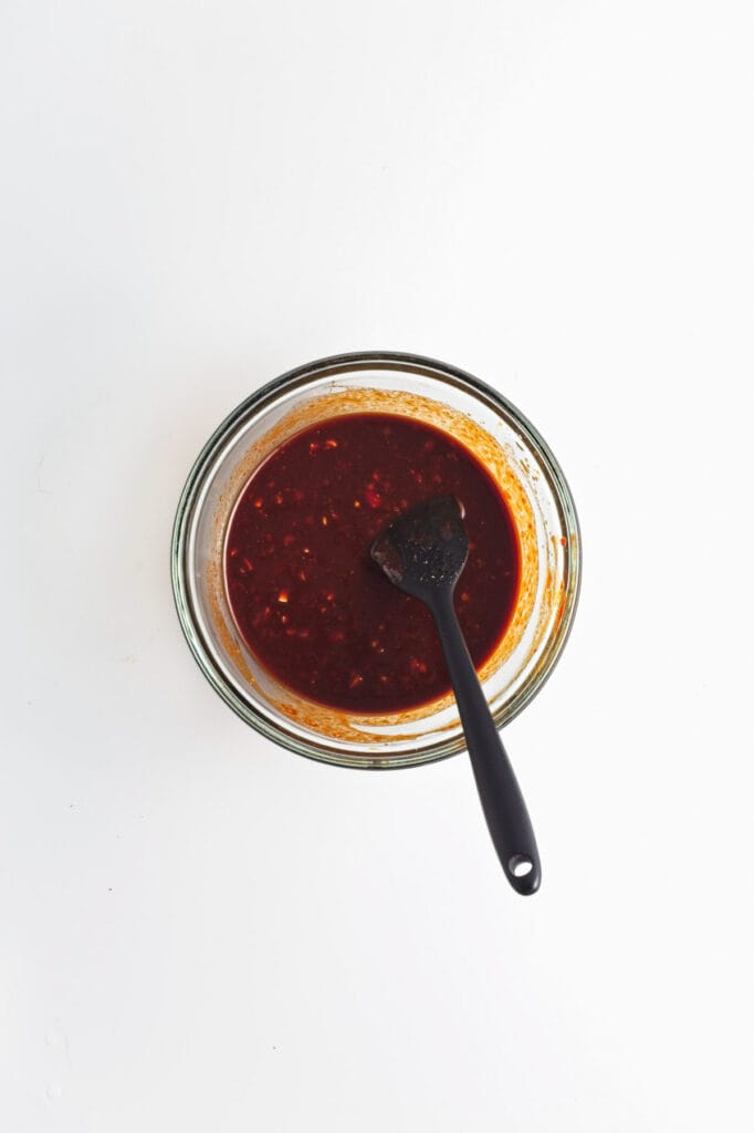 A bowl of sauce with a spoon in it, perfect for gochujang or cabbage.