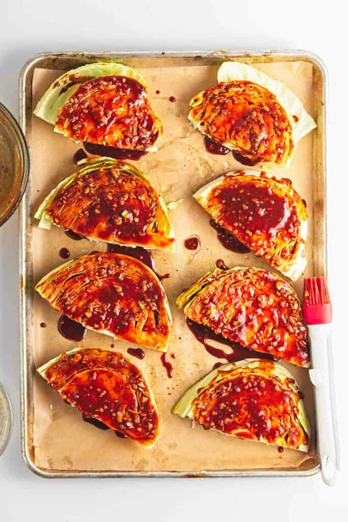 A baking sheet with sliced cabbage and bbq sauce.