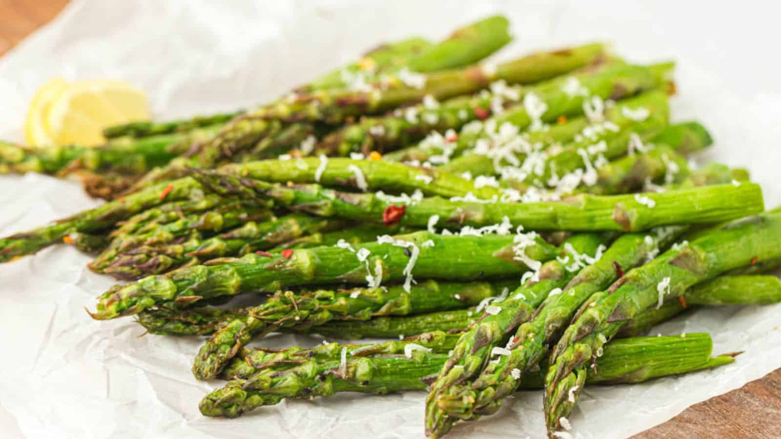 An air fryer pile of asparagus with grated cheese.