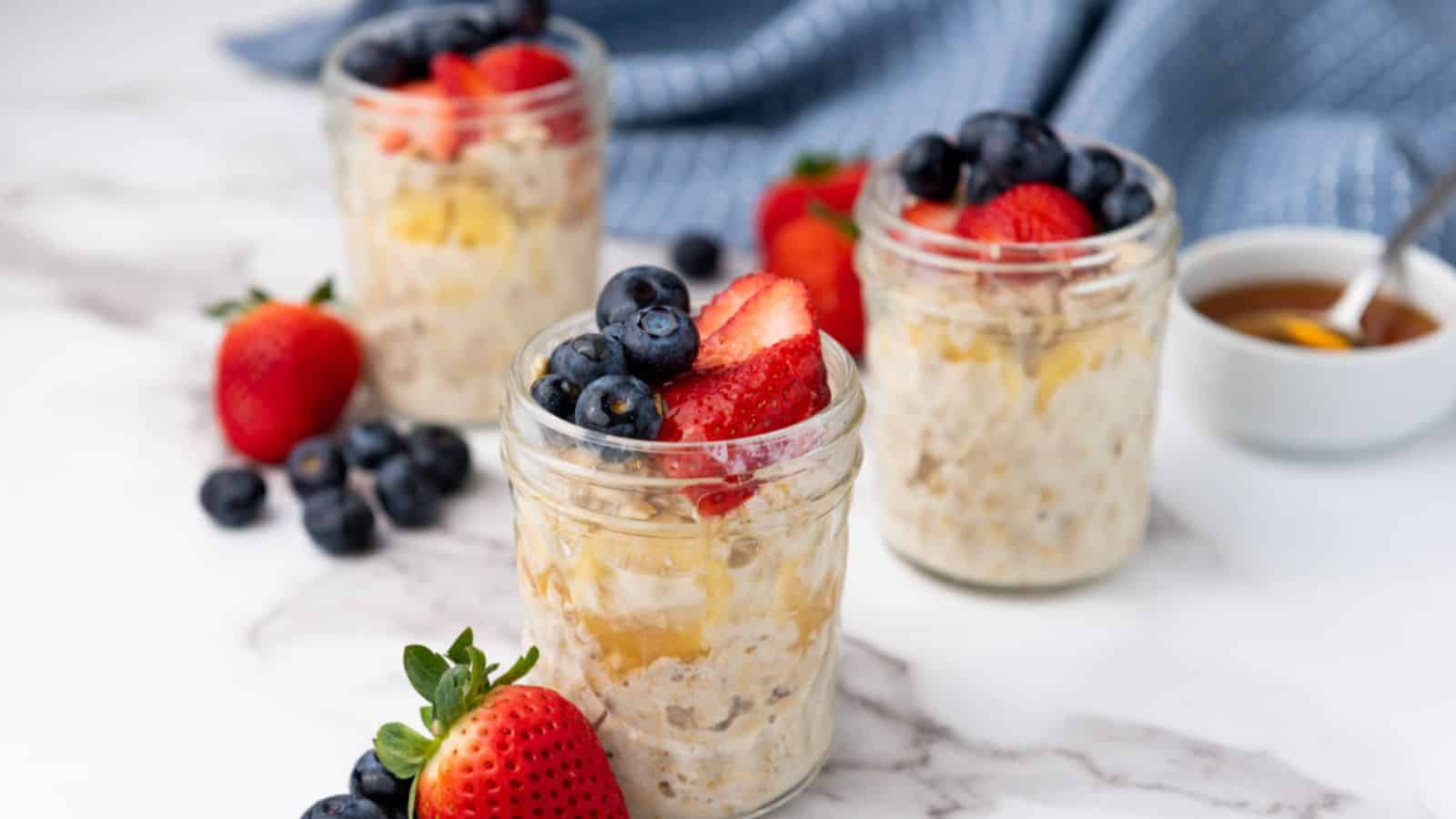 Three jars of oatmeal with berries and maple syrup.