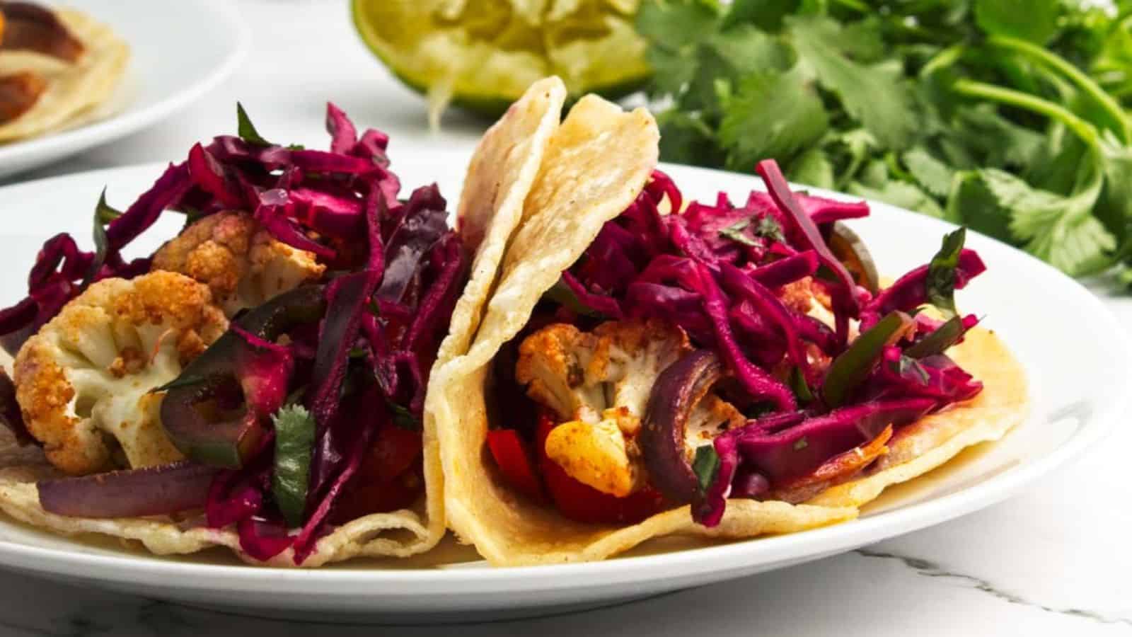 A plate of tacos with red cabbage and cauliflower slaw.