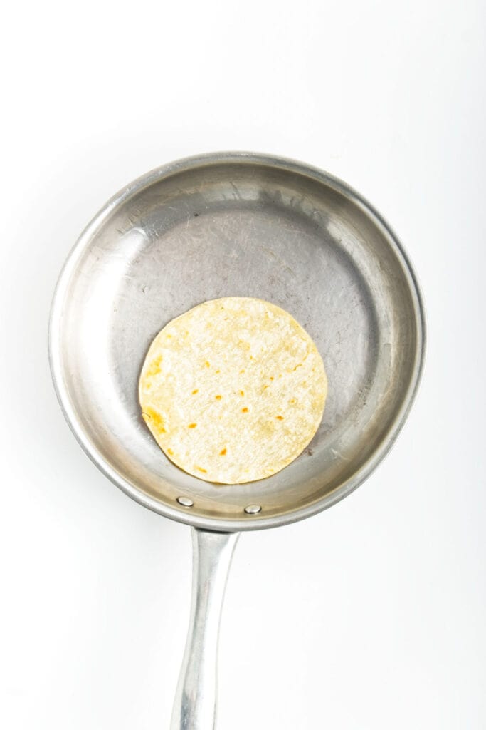 A tortilla with roasted cauliflower in a frying pan on a white background.