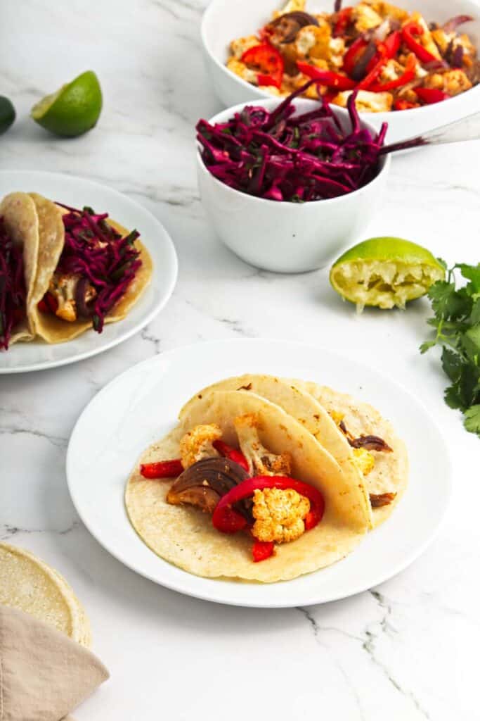 A plate of roasted cauliflower tacos with red cabbage and Swiss chard.