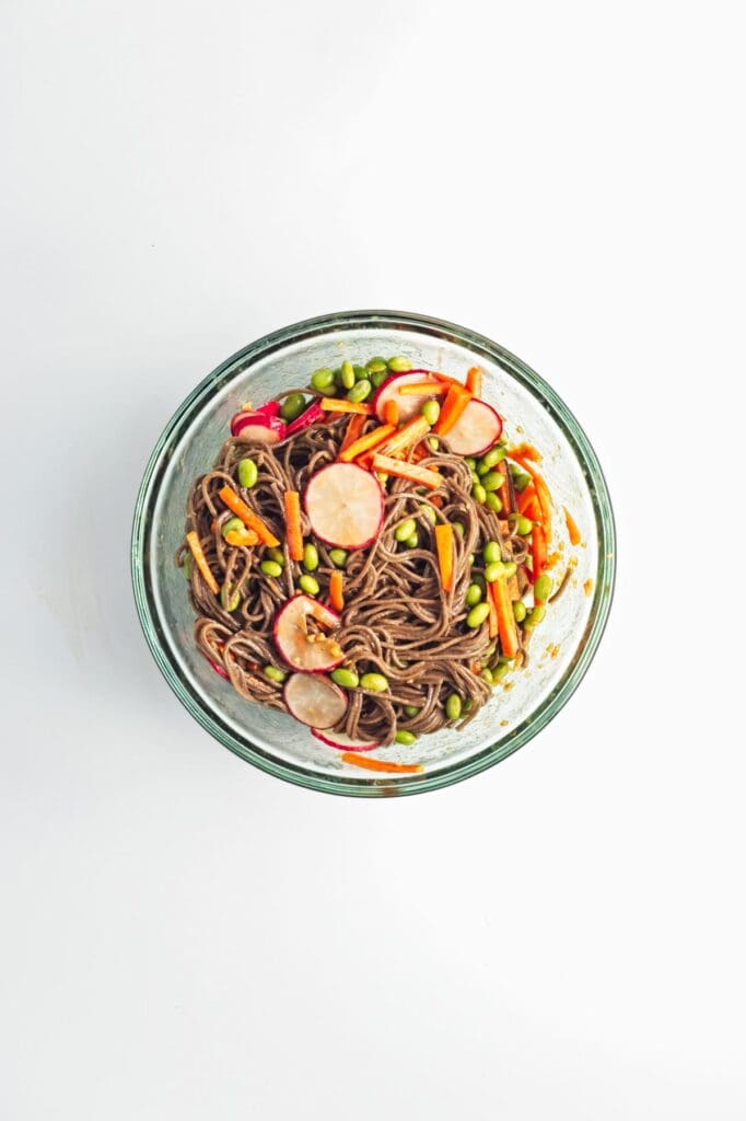 A bowl of soba noodles with vegetables.
