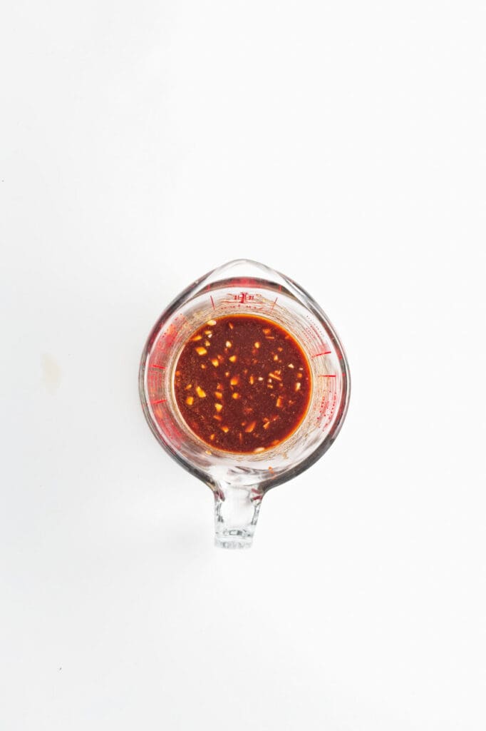 A measuring cup with soy sauce and seasonings.
