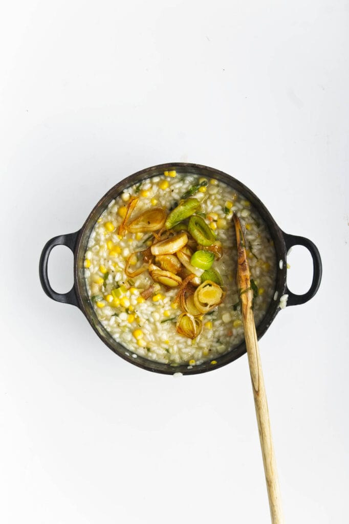 A bowl of sweet corn and leek risotto with a spoon.
