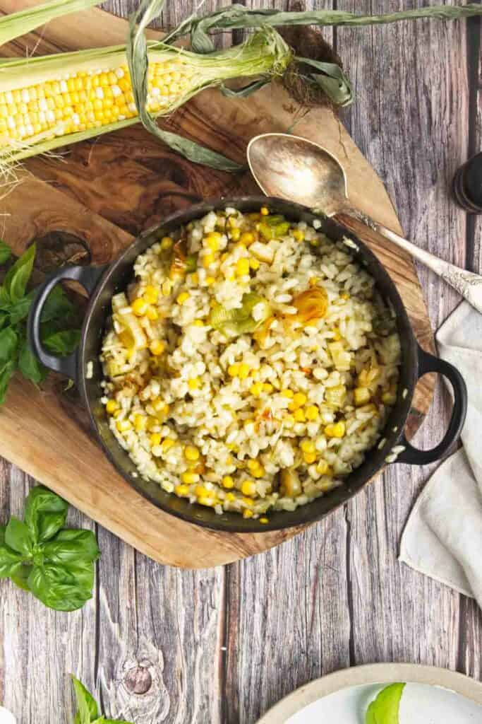 Sweet corn and leek risotto on a wooden cutting board.