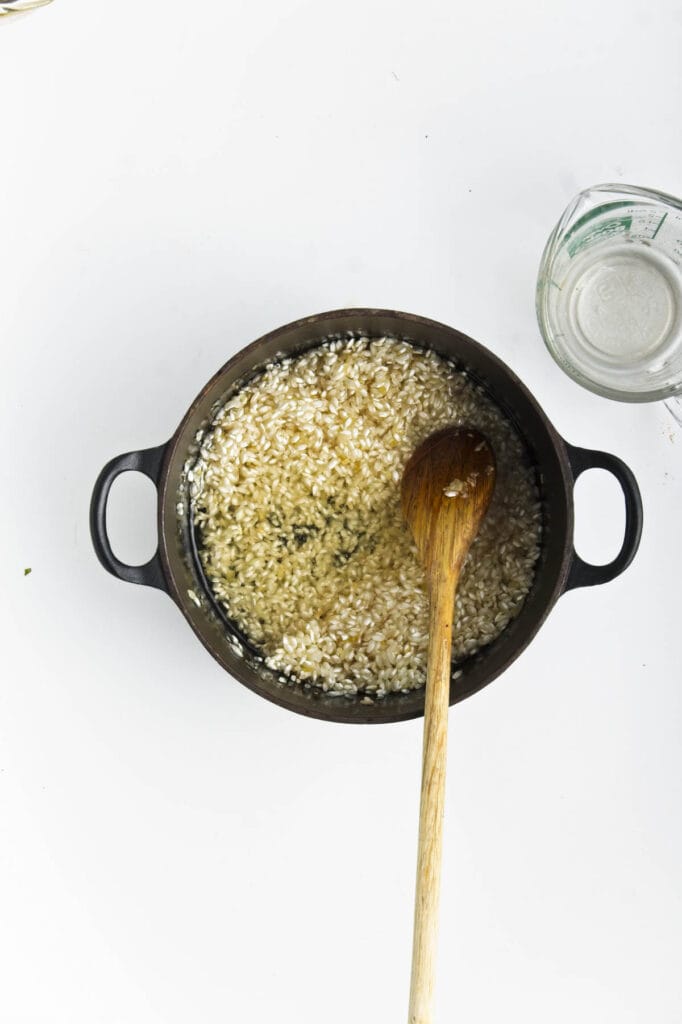 A pot with rice for a sweet corn and leek risotto dish.
