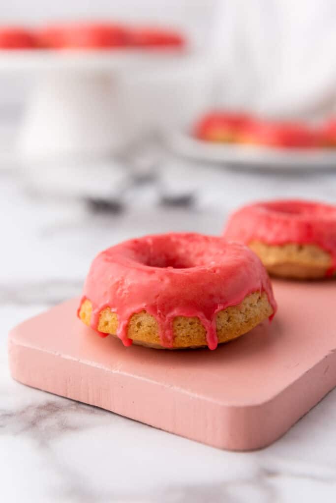 Vegan Baked Vanilla Donuts on a pink board.