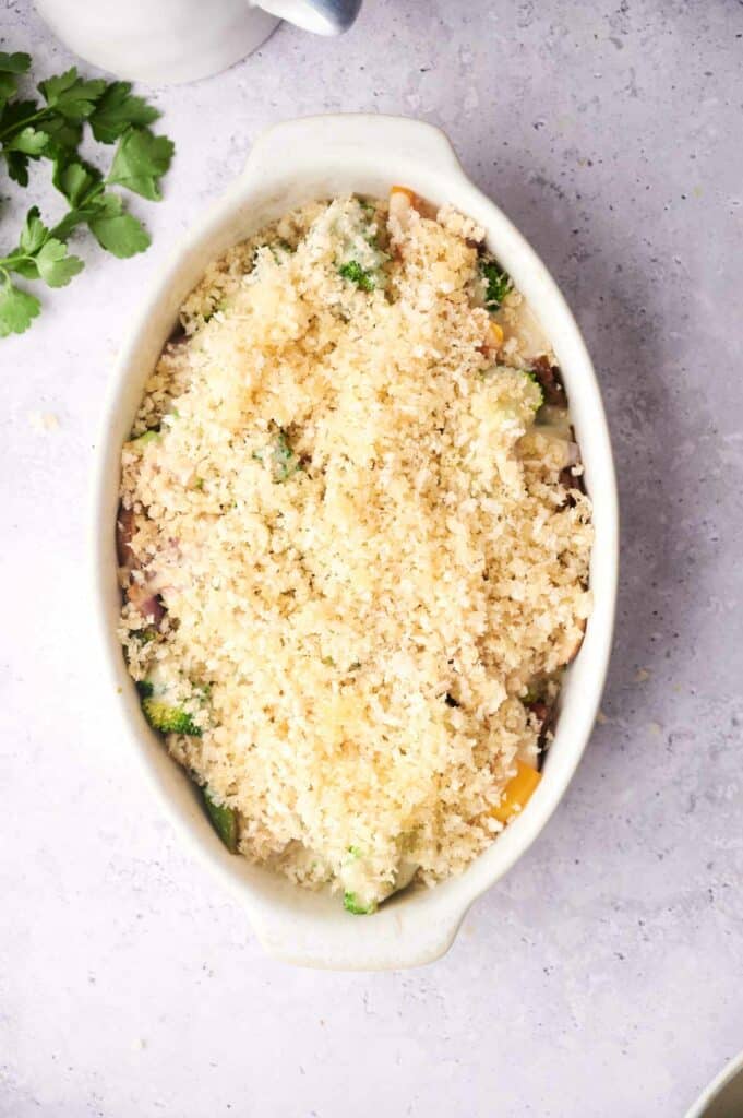 A baked vegetable casserole with a golden breadcrumb topping in an oval dish.