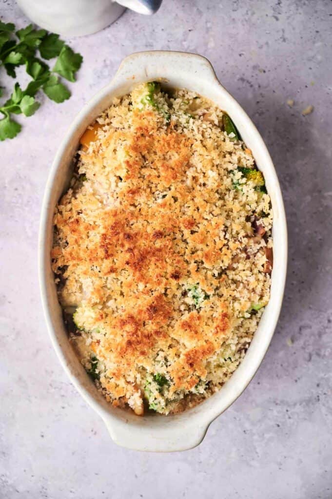 A baked vegetable casserole with a golden-brown breadcrumb topping in a white dish.