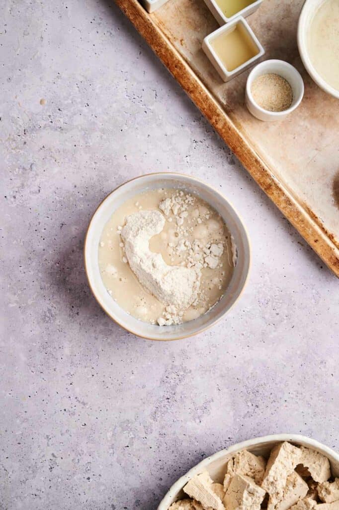 Flour and milk in a bowl for a vegan tofu recipe.