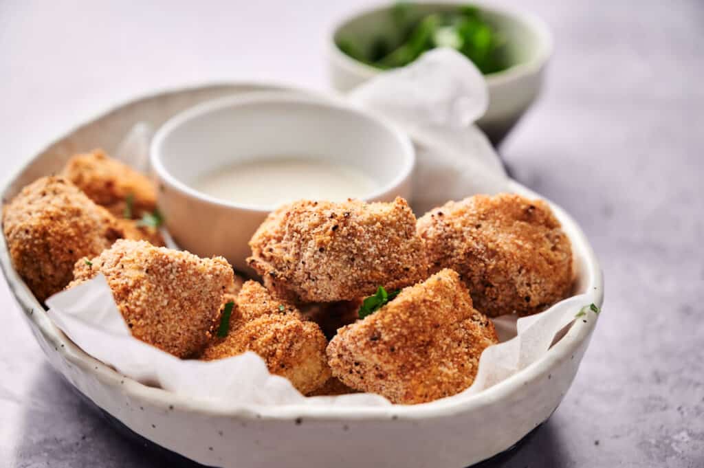 Vegan Chicken Nuggets in a white bowl with dip.