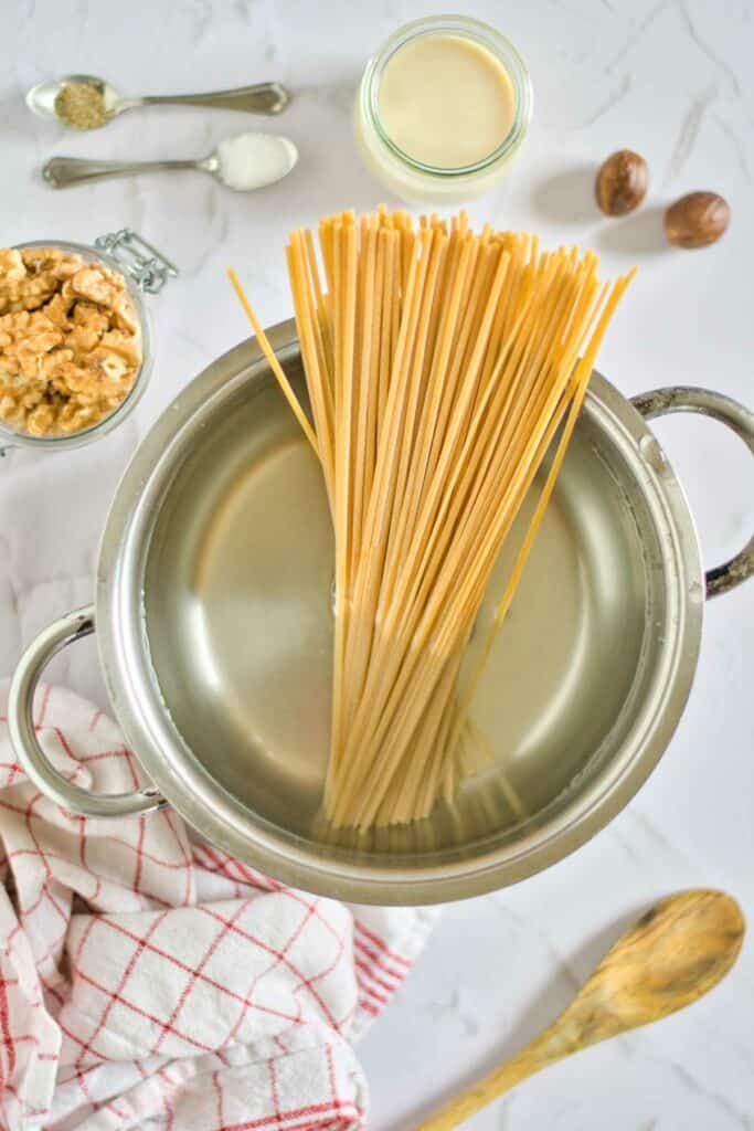 Pasta in a pan with nuts and a spoon.