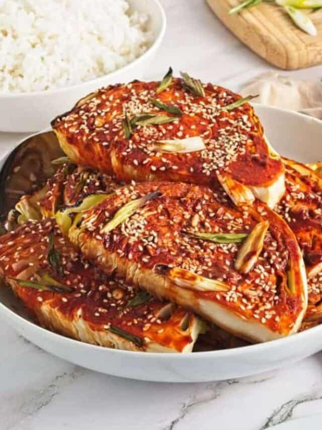 Spicy korean kimchi served in a bowl, garnished with sesame seeds and green onions.