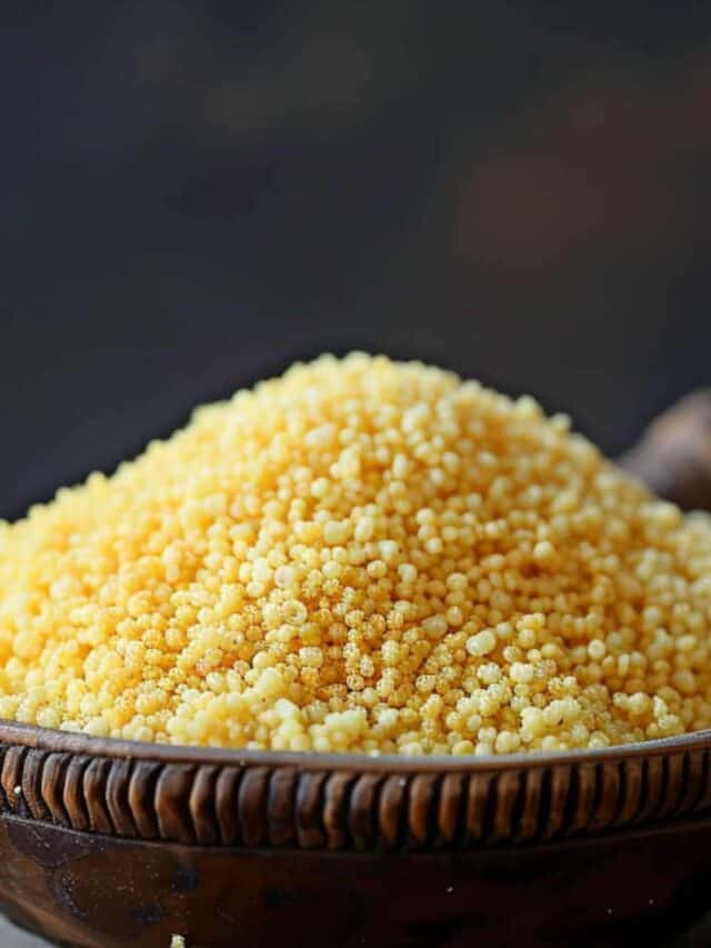 A bowl of yellow couscous in a wooden bowl.
