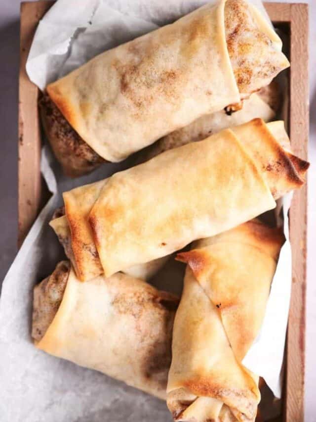 Three freshly baked burritos on parchment paper.