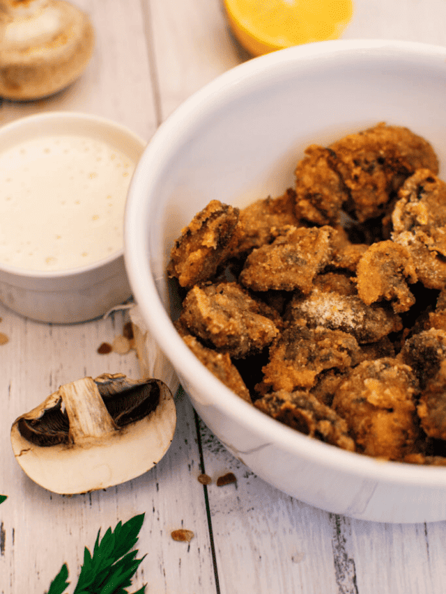A bowl of fried mushrooms served with a side of dipping sauce.