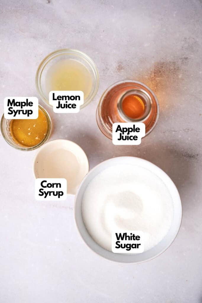 Labeled ingredients on a surface containing maple syrup, lemon juice, apple juice, vegan honey, and white sugar.