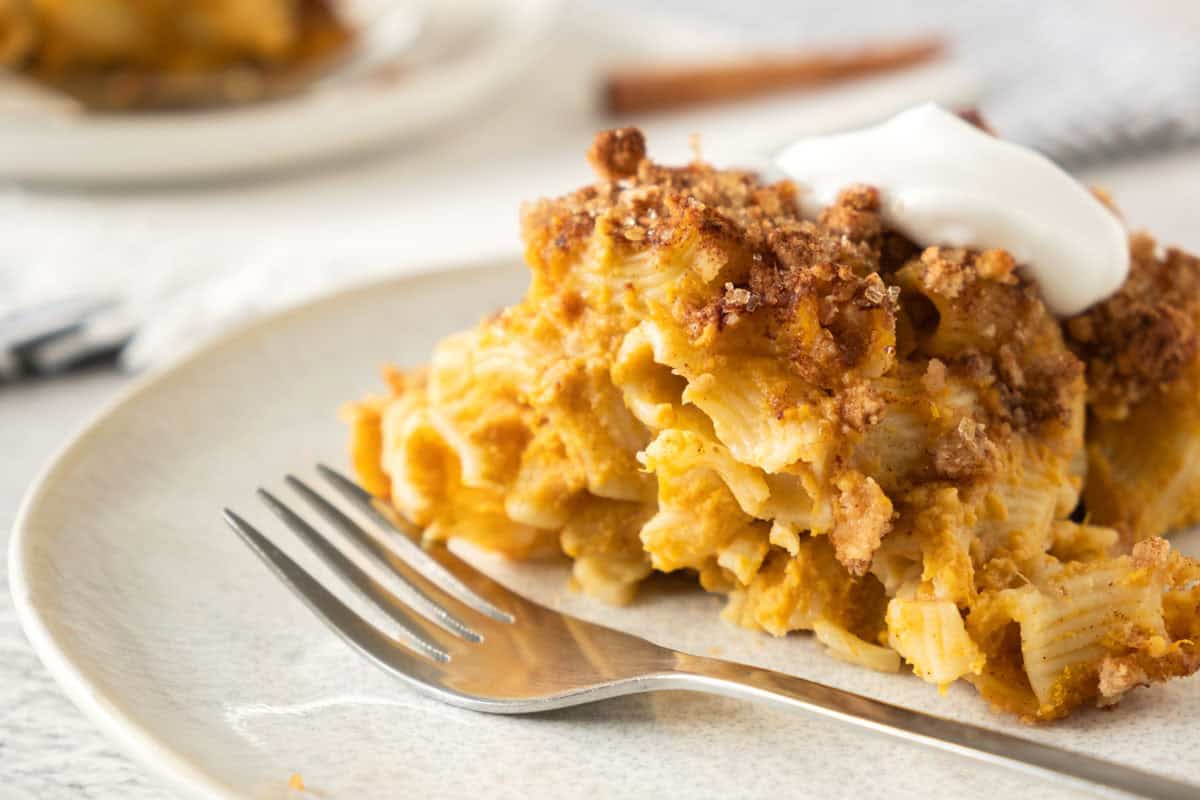A plate of baked pasta with a crispy, browned topping and dollops of white sauce.