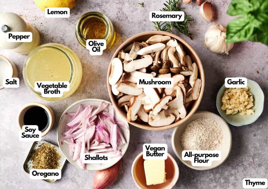 A flat lay of labeled ingredients for Vegan Mushroom Gravy, featuring mushrooms, shallots, vegetable broth, soy sauce, vegan butter, spices, garlic, olive oil, and flour.
