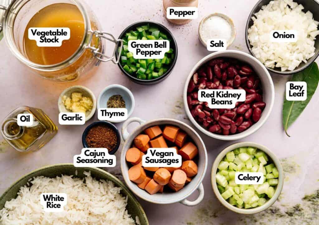 Top-down view of labeled ingredients for Vegan Gumbo, featuring rice, vegan sausages, beans, vegetables, spices, and vegetable stock in a vibrant Cajun dish.