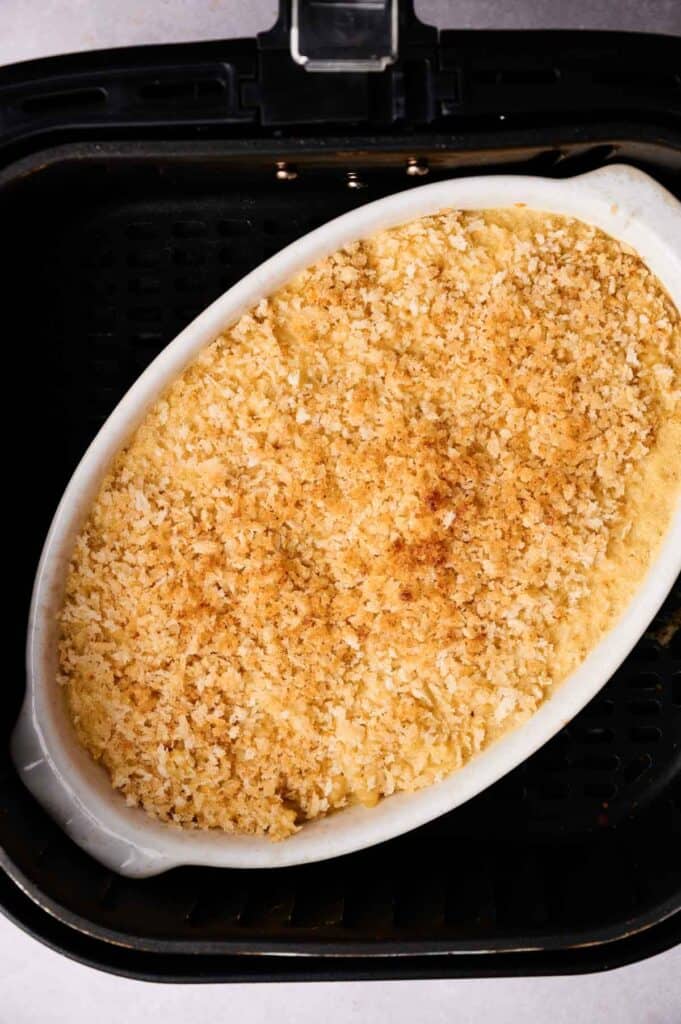 Oval white dish with a golden-brown breadcrumb topping, this Air Fryer Mac and Cheese sits perfectly inside the air fryer basket.
