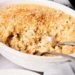 Air Fryer Mac and Cheese baked in a white dish, topped with golden breadcrumbs, and served with two spoons.