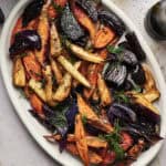 A white oval platter filled with Air Fryer Roasted Root Vegetables, including carrots, parsnips, and beets, all perfectly crisp and garnished with fresh herbs.