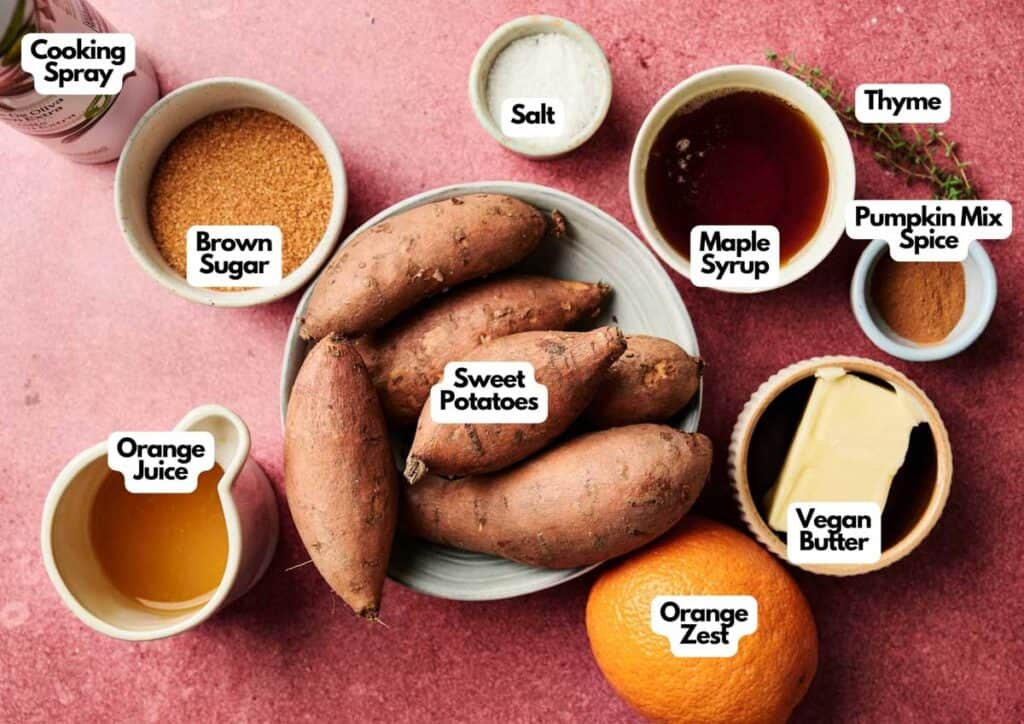 A bowl of sweet potatoes sits surrounded by labeled ingredients for Sweet Potato Casserole with Orange Juice: cooking spray, brown sugar, salt, maple syrup, thyme, pumpkin spice mix, vegan butter, and orange zest.