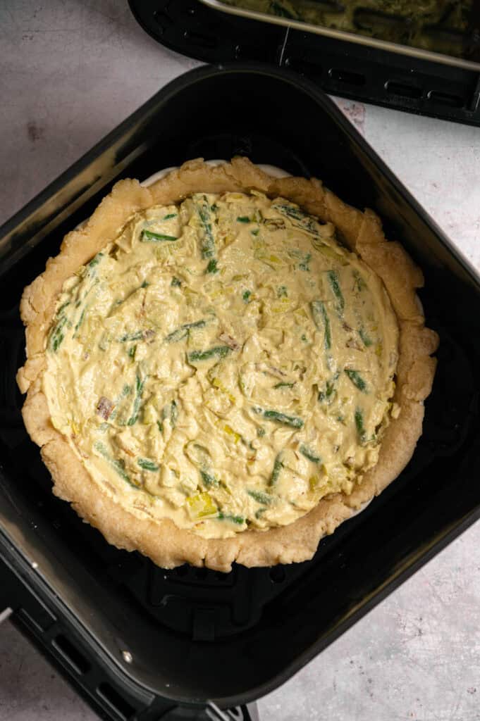 Air Fryer Vegan Asparagus Quiche with a crumbly crust sits in the basket, unbaked and ready to be cooked.