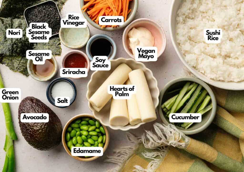Sushi Bowl ingredients arranged in bowls and plates, including sushi rice, cucumber, hearts of palm, avocado, edamame, and various sauces and seasonings&mdash;all clearly labeled with text.